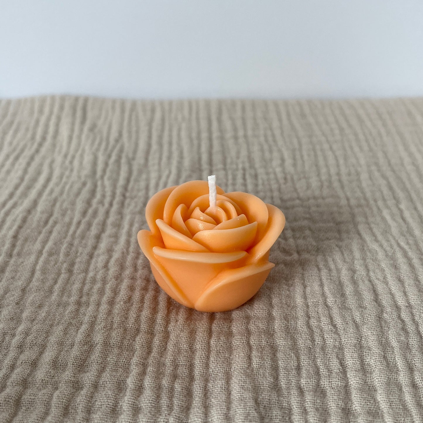Apricotfarbene kleine Kerze in Form einer Rose.