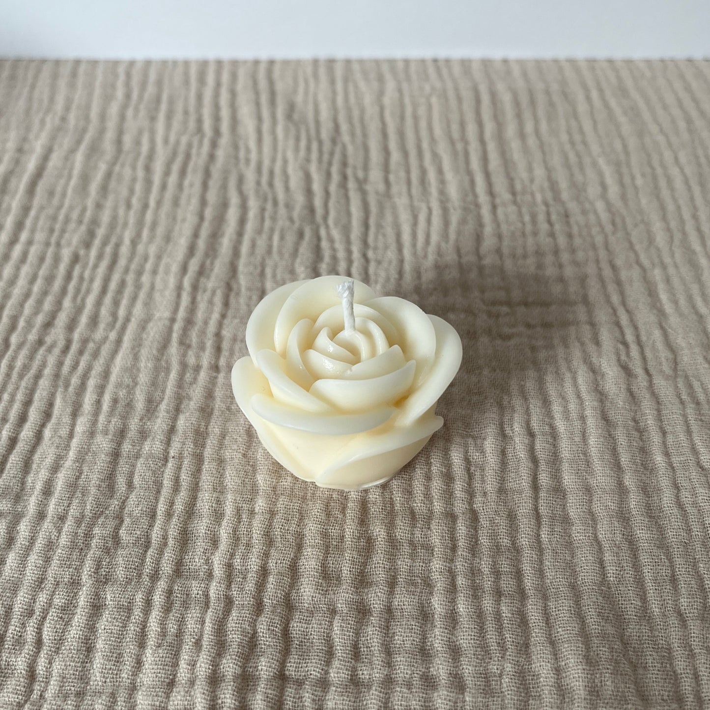 Kleine weiße Rapswachskerze in Form einer Rose.