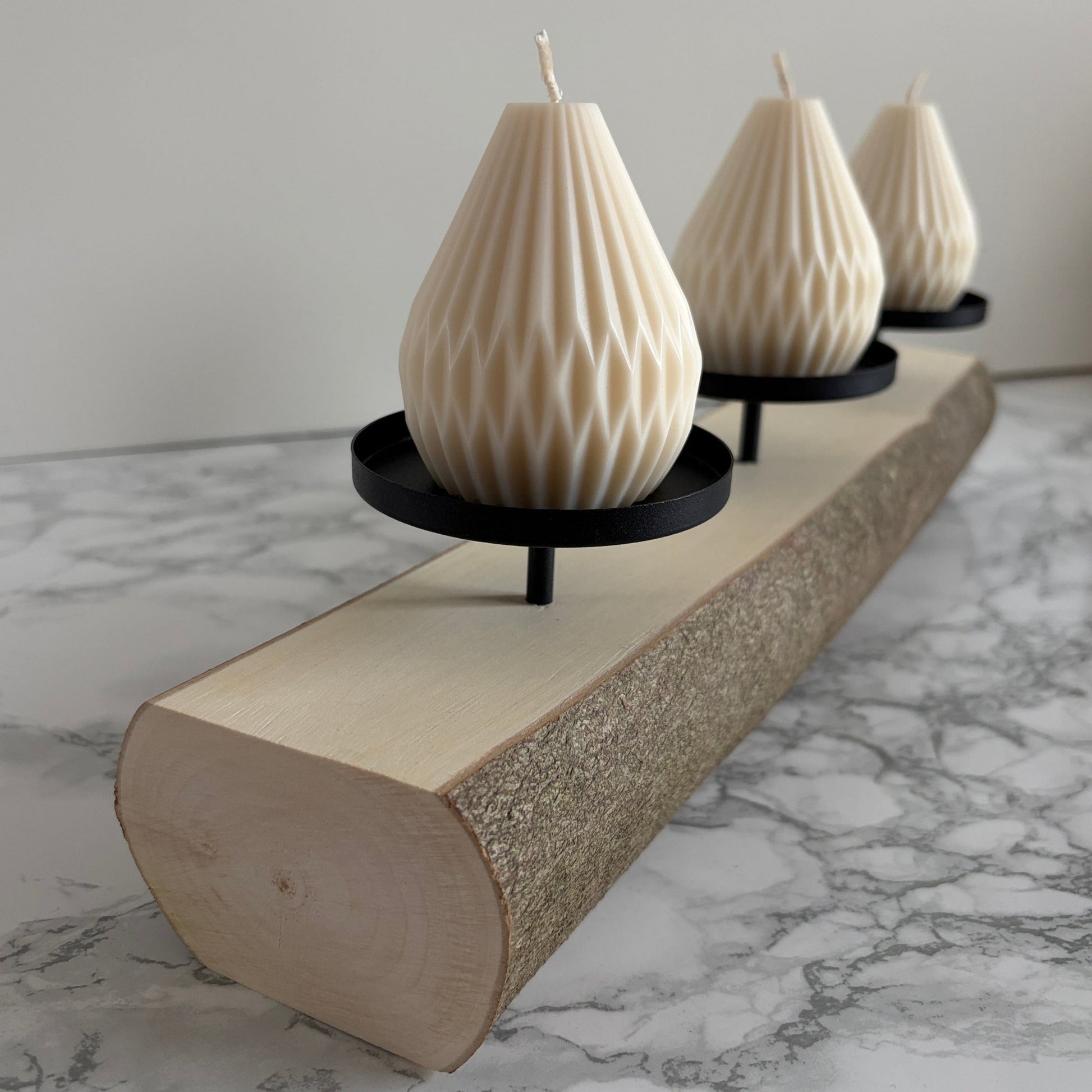 3er Holzstamm als Kerzenstaender mit Kerzen drauf. Seitlich fotografiert.