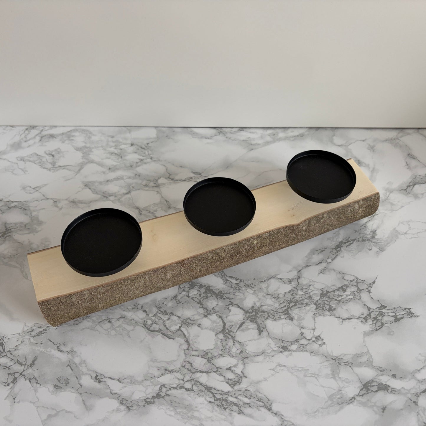 3er Kerzenhalter aus einem Holzstamm mit drei schwarzen Kerzentellern.