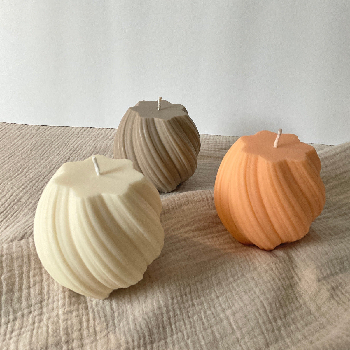3 große Wellenkerze aus Rapswachs in den Farben cremeweiß, apricot und beige.