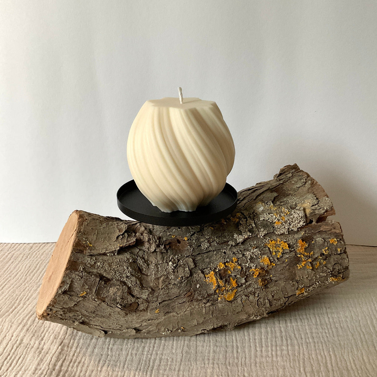 Weiße XL Wellenkerze auf einem Holzstamm mit Kerzenhalter.