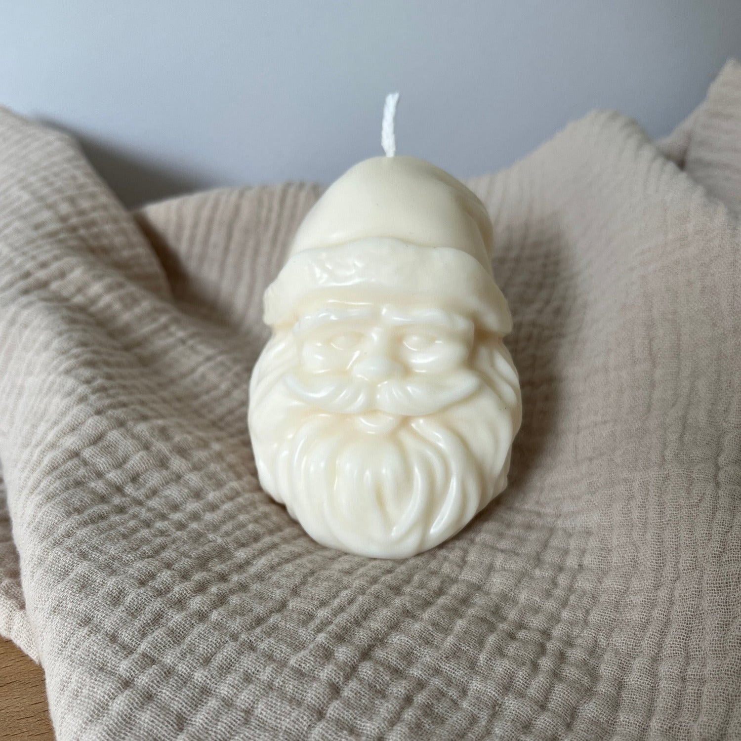 Weiße Rapswachskerze in Form eines Weihnachtsmannkopfes.