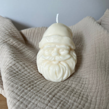 Weiße Rapswachskerze in Form eines Weihnachtsmannkopfes.